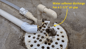 Water softener line with a one-and-a-half inch air gap above drain in floor.