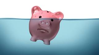A pink piggy bank with an unhappy expression is mostly submerged underwater, with only one eye and ears visible above.